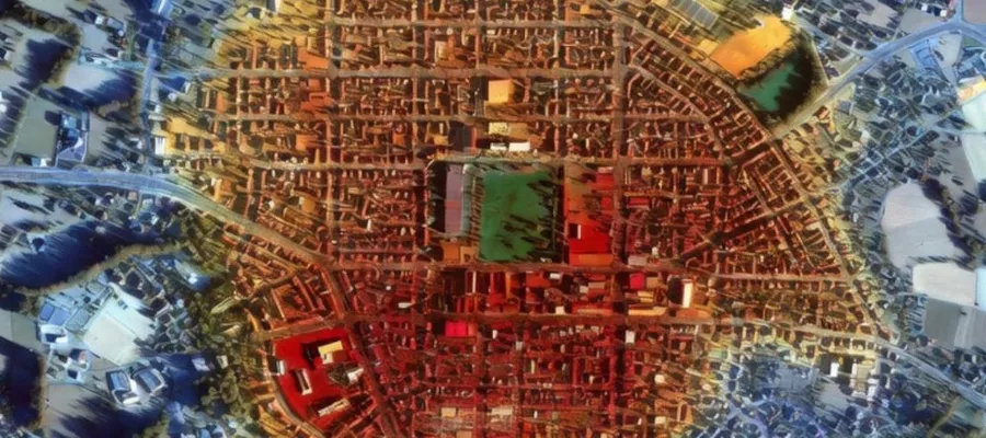 Luftaufnahme einer Stadt mit einem klar erkennbaren, rechteckigen Straßennetz und umliegenden landwirtschaftlichen Flächen